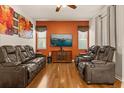 Cozy living room with theater seating, warm wood floors, and bright accent wall at 11316 Rapallo Ln, Windermere, FL 34786