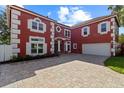 Striking two-story red house with white trim, attached garage, and brick paved driveway at 1254 Shelter Rock Rd, Orlando, FL 32835