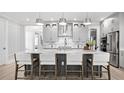 Modern kitchen featuring a large island with seating, stainless steel appliances, and stylish pendant lighting at 1613 Bellagio Loop, Tavares, FL 32778