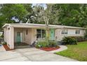 Single-story home with pink exterior, lush landscaping, covered carport, and eye-catching light teal front door at 3007 Huntington St, Orlando, FL 32803