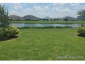 A lovely backyard featuring a serene pond view, lush green grass, and sunny skies at 356 Quarry Rock Cir, Kissimmee, FL 34758