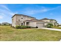 Side view of a two-story home showing the lawn and a two-car garage on a sunny day at 356 Quarry Rock Cir, Kissimmee, FL 34758