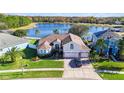 Beautiful, charming pink home with three-car garage, lush lawn, and serene lake view at 10642 Cloudview Dr, Orlando, FL 32825