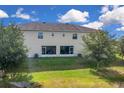 Home's backyard featuring a lush lawn, mature trees, and a view of the sliding glass doors at 316 Primrose Dr, Davenport, FL 33837