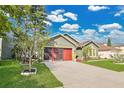 Beautiful home exterior with green lawn and a red garage door under a sunny sky at 321 Thomasdale Ave, Haines City, FL 33844