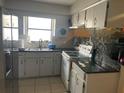 A functional kitchen featuring tile floors, white cabinets, and a stainless steel refrigerator, offering a practical cooking space at 3347 Timberline W Rd, Winter Haven, FL 33880