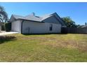 View of home's siding, roof, and grassy backyard with wood fence and clear sky at 549 Silvergate Loop, Lake Mary, FL 32746