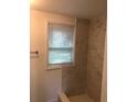 Shower featuring a neutral colored tile surround, modern fixtures, and a bright window with privacy blinds at 647 Madison Ave, Daytona Beach, FL 32114