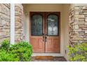 A close up of the wooden double front door framed with stone and decorative metal scrollwork at 9736 Hatton Cir, Orlando, FL 32832
