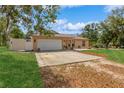 Charming single-story home featuring a spacious driveway, lush lawn, and decorative landscaping at 1395 Deland Ave, Orange City, FL 32763