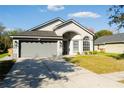 Well-maintained home featuring a manicured lawn, mature trees, and a two-car garage at 149 Southampton Dr, Kissimmee, FL 34744