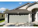 Two-car garage with decorative windows and exterior lighting for curb appeal at 149 Southampton Dr, Kissimmee, FL 34744