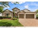 Charming stone home featuring a three-car garage, brick paver driveway and lush landscaping at 16761 Broadwater Ave, Winter Garden, FL 34787