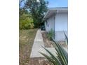 A concrete pathway leads along the side yard of a house with green foliage and a glimpse of a utility box at 2233 N Normandy Blvd, Deltona, FL 32725