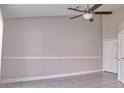Neutral living room with tiled floor, ceiling fan and adjacent white door at 2536 Woodgate Blvd # 202, Orlando, FL 32822