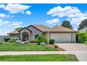 Inviting single-story home with manicured lawn, vibrant landscaping, brick driveway, and a two-car garage at 4571 Abaco Dr, Tavares, FL 32778