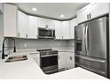 Beautiful kitchen features white cabinets, stainless steel appliances, quartz countertops, and a modern faucet at 5805 Hutton Dr, Orlando, FL 32808