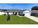 Inviting home featuring lush green lawn, concrete driveway, and attached two-car garage at 15476 Sw 34Th Court Rd, Ocala, FL 34473