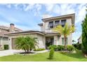 Beautiful home featuring a two-car garage, manicured lawn, and lush tropical landscaping at 15947 Vetta Dr, Bella Collina, FL 34756