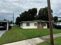View of the home's front exterior with its well-manicured lawn and ample parking with covered carports at 1822 Williams Manor Ave, Orlando, FL 32811