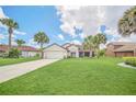 Beautiful home with lush green lawn, mature palm trees, and a long driveway leading to the garage at 2445 Ravendale Ct, Kissimmee, FL 34758