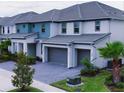 A row of modern homes are presented with manicured lawns, palm trees, and stylish teal and gray exterior paint at 3880 Sonoma Blvd, Kissimmee, FL 34741