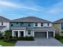 A modern two-story home boasts a three-car garage, well-maintained lawn, and stylish teal and gray color scheme at 3880 Sonoma Blvd, Kissimmee, FL 34741