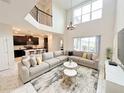 Bright living room with soaring ceilings, a large sectional sofa, and views into the adjacent open-plan kitchen at 671 Drop Shot Dr, Davenport, FL 33896