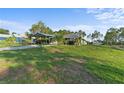 Beautiful home with a covered parking area, lush green lawn, and mature trees on a sunny day at 6975 Maverick Trl, St Cloud, FL 34771