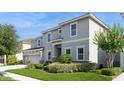 Beautifully landscaped front yard with a two-story home featuring a three-car garage at 7017 Oakwood St, Davenport, FL 33837