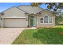 Charming single-story home featuring a well-manicured lawn and a neutral stucco exterior with a green front door at 714 Home Grove Dr, Winter Garden, FL 34787