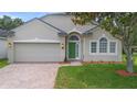 Inviting single-story house boasting a neatly maintained front lawn and a neutral stucco exterior with a green front door at 714 Home Grove Dr, Winter Garden, FL 34787