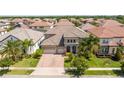 Stunning aerial view of a home with a tile roof, three-car garage, and lush landscaping at 8419 Pippen Dr, Orlando, FL 32836