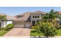 Charming two-story home featuring a brick-paved driveway, lush landscaping, and an attached three-car garage at 8419 Pippen Dr, Orlando, FL 32836