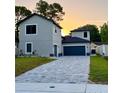 Beautiful home with a paved driveway, modern architecture, and a lovely sunset backdrop at 107 Grove St, Orlando, FL 32835