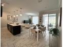 Bright, open-concept living space with modern tile floors, a sleek kitchen island, and a dining area at 1078 Splash Shot Pl, Davenport, FL 33896