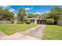 View of home with a well-maintained lawn, trees, and driveway leading to a screened in front porch at 1202 Randolph St, Sanford, FL 32771