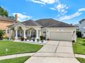 Well-maintained single-story home featuring a two-car garage, lush lawn, and decorative flower beds along the entrance at 14036 Cherry Bush Ct, Orlando, FL 32828