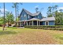 Inviting blue home with a wraparound porch and manicured front lawn at 14205 Conifer Dr, Orlando, FL 32832