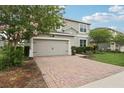 Charming two-story home with a brick driveway, manicured lawn and beautiful flowering tree at 1450 Chelsea Manor Cir, Deland, FL 32724