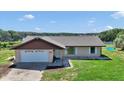 Well-maintained home featuring an attached garage and a vibrant green lawn at 16386 Se 156Th Place Rd, Weirsdale, FL 32195