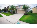 Inviting home exterior featuring a manicured lawn, lush landscaping, and a spacious driveway leading to a garage at 1748 Thetford Cir, Orlando, FL 32824