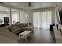 Bright living room with a comfortable sectional sofa, sheer curtains, and wood-look floors, offering a view of the pool at 17614 Woodcrest Way, Clermont, FL 34714
