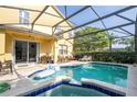 Inviting screened-in pool and spa area with a dining table, chairs and grill outside at 17614 Woodcrest Way, Clermont, FL 34714