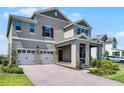 Attractive home featuring a three-car garage, front porch, beautiful pavers, and well-maintained landscaping at 18309 Oliver Twist Way, Winter Garden, FL 34787