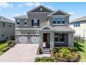 Charming two-story home with a three-car garage, brick paver driveway, and manicured landscaping at 18309 Oliver Twist Way, Winter Garden, FL 34787