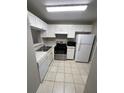 A compact kitchen with white cabinets, appliances, and tile floors at 2236 Stonington Ave # 2236, Orlando, FL 32817