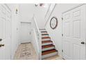 Bright foyer showcasing wood stairs, white doors, neutral tile floors, and modern decor at 3331 Windsor Lake Cir, Sanford, FL 32773