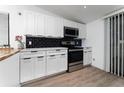 Modern kitchen featuring stainless steel appliances, white cabinets, and a stylish black backsplash at 415 S Lancelot Ave, Orlando, FL 32835