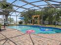 Backyard pool with screened enclosure, brick pavers and tropical landscaping at 437 Bridgewater Court, Kissimmee, FL 34758